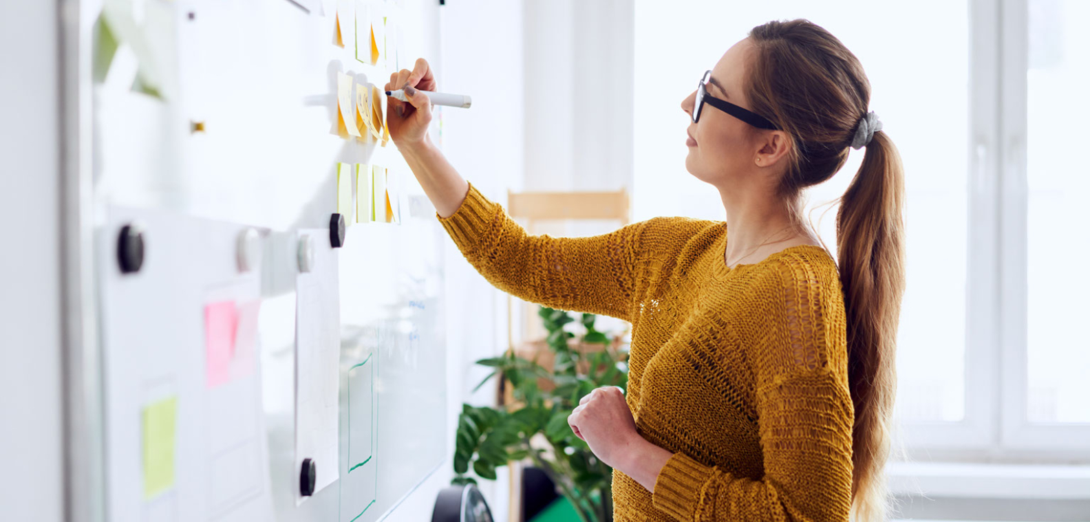 Woman brainstorming a media plan on a white board.